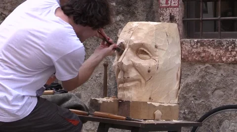 Wood carver with a chisel on left eye of sculpture - Public Carving Competition Video stock 51367120