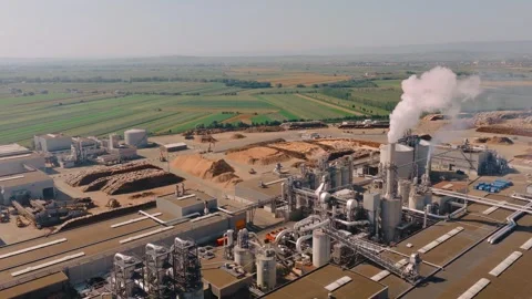 Wood chip processing plant emitting smoke in rural landscape Stock Footage 315168815