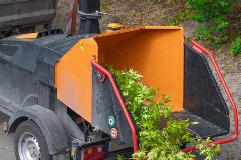 A wood chipper machine shredding tree branches into smaller pieces Stock Photos