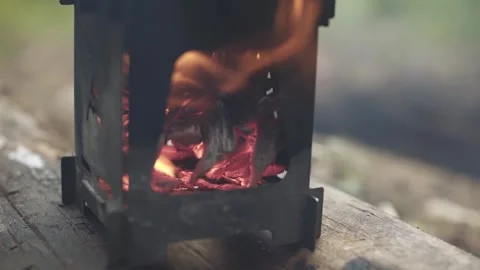 Wood chips burning in a portable folding wood stove in the forest. Close-up. Stock Footage 280226371