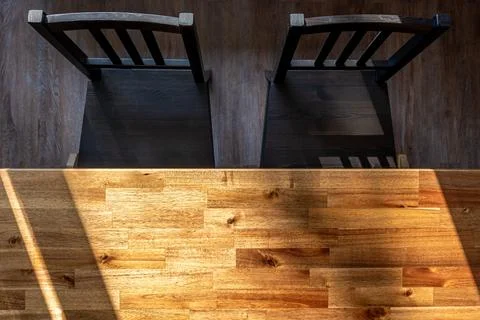 Wood dining table with two black chairs. Top view of sunlit furniture and d.. Stock Photos