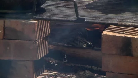 Wood fire in a makeshift stove on bricks over which a metal grill was placed Stock Footage 146543007