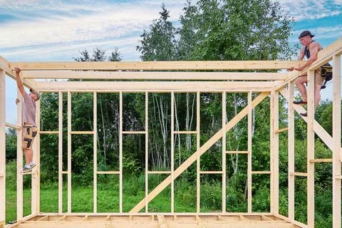 Wood frame construction with young builders positioning ceiling beams and u.. Stock Photos