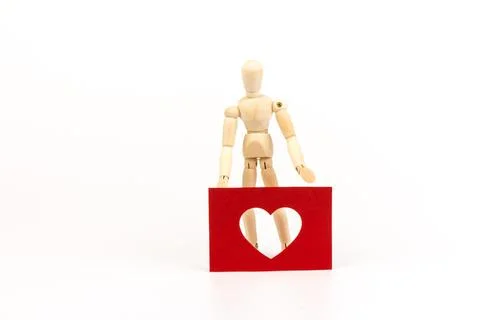 Wood man figure holding  shape of  heart on white background with copy space. Stock Photos