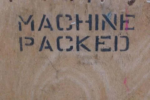 Wood panel with the words machine packed stencilled in black Stock Photos