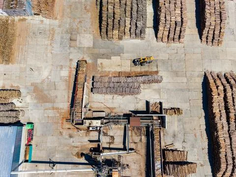 Wood processing area during daytime with machinery and stacked wood in an i.. Stockfoto's