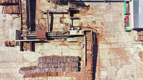 Wood processing area with timber stacked and machinery in use at a lumber yard Stock Footage 344300730
