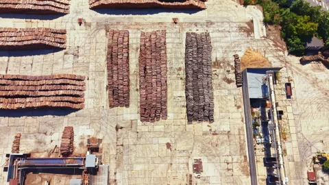Wood processing facility shows stacks of timber and machinery during bright Stock Footage 341576109