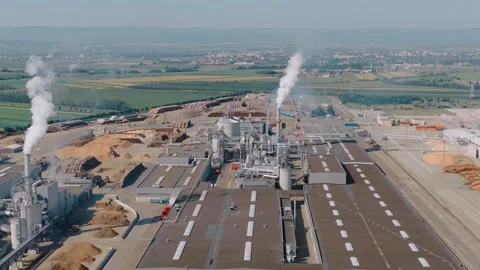 Wood processing plant emitting smoke from chimneys in rural landscape Stock Footage 315168796