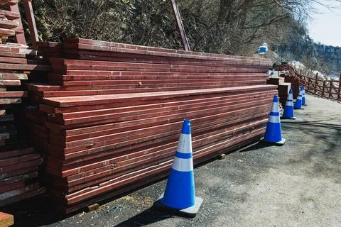 Wood stack by the path near a construction site with safety cones during da.. Stock Photos
