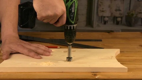 Wood Worker using an electric hand drill to drill a hole through the plank Stock Footage