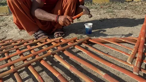 Wood worker using hammer to nail and coloring bamboo stick making fence Stock Footage 229407140