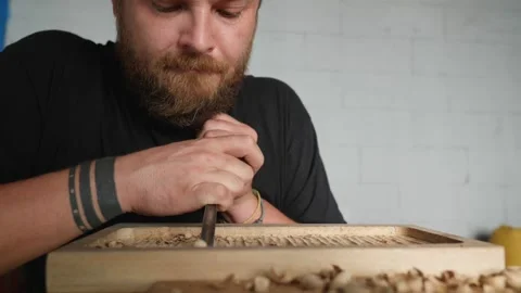 A woodcarver processes a walnut board with a chisel. artisan makes a tea tray Stock Footage 144244106