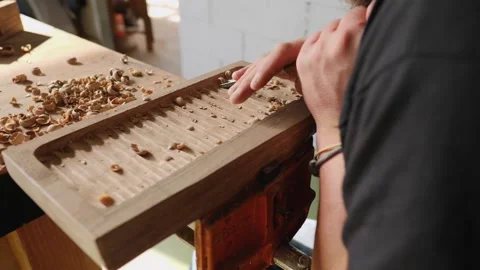 A woodcarver processes a walnut board with a chisel. artisan makes a tea tray Stock Footage 144244139