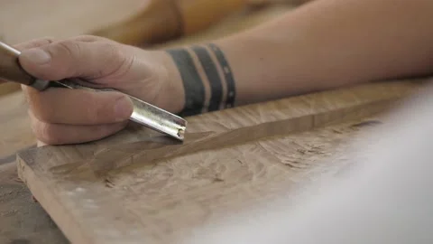 A woodcarver processes a wooden board with a chisel and mallet. craftman maki Stock Footage 137149732