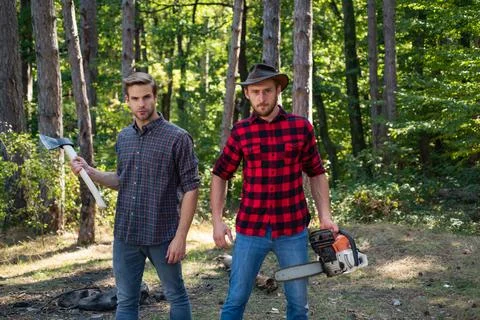 Woodcutters with chainsaw lumberjacks with axe. Hipsters men on serious face Stock Photos
