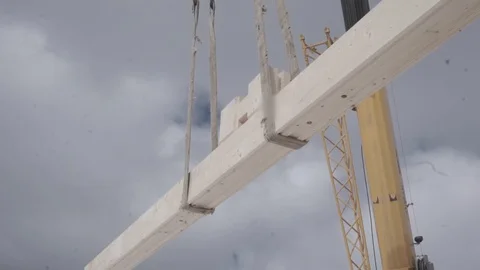 The wooden bar is moved using a crane. The builder takes the timber. Stock Footage 106628168