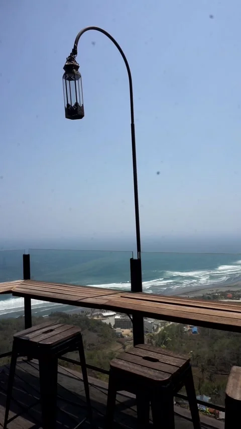 Wooden bar table and stool seating setup on an open-air deck overlooking Видео 346885853