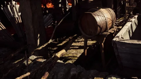 Wooden barrel on a stand inside an old barn with scattered tools and sunlight Stock Footage 345063578