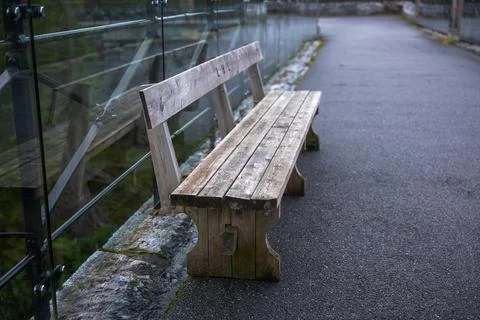 Wooden bench along paved path with glass railing overlooking water, Norway Stock Photos