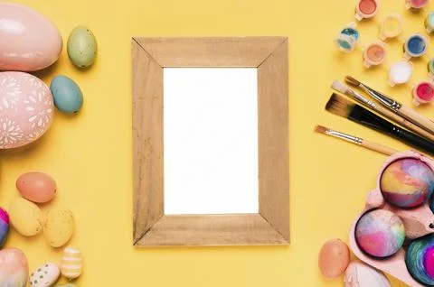 Wooden blank white frame with easter eggs paint brushes watercolor paint yellow Foto stock