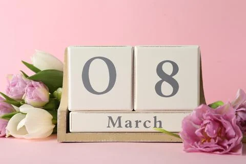 Wooden block calendar with date 8th of March and tulips on pink background. I Stock Photos