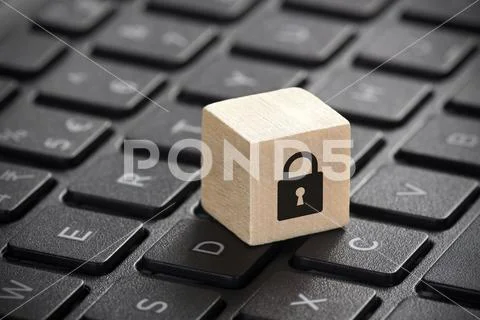 Wooden block with lock graphic on laptop keyboard. Computer security concept. Stock Photos