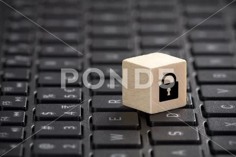 Wooden block with lock graphic on laptop keyboard. Computer security concept. Stock Photos