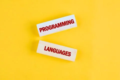 Wooden blocks display the words programming and languages against a bright ye Stock Photos