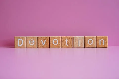 Wooden blocks form the text "Devotion" against a pink background. Stock Photos