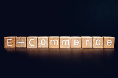 Wooden blocks form the text "E-Commerce" against a black background. Stock Photos