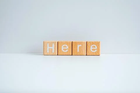 Wooden blocks form the text "Here" against a white background. Stock-Fotos