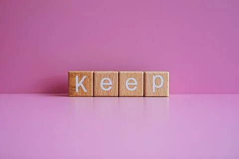 Wooden blocks form the text "Keep" against a pink background. Stock Photos