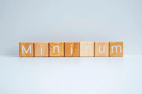 Wooden blocks form the text "Minimum" against a white background. Stock Photos