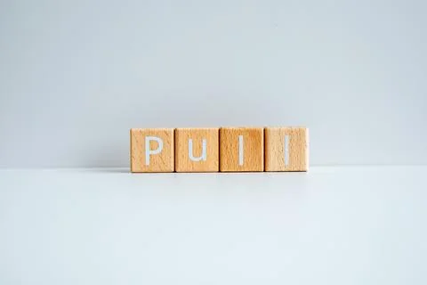 Wooden blocks form the text "Pull" against a white background. Stock-Fotos