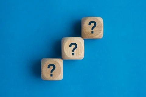 Wooden blocks with question marks stacked vertically on a blue background, .. Stock Photos