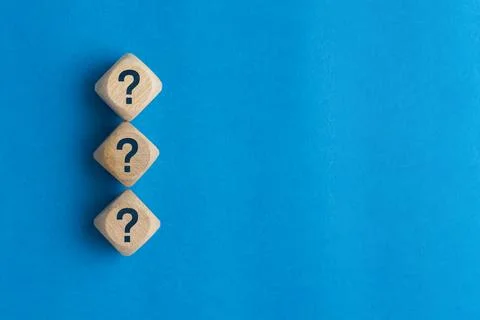 Wooden blocks with question marks stacked vertically on a blue background, .. Stock Photos