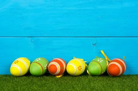 Wooden blue background with easter eggs painted in vibrant colors. Stock Photos