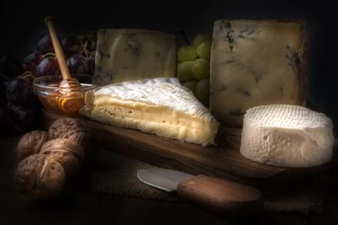 Wooden board with cheeses, grapes, nuts and honey Stock Photos