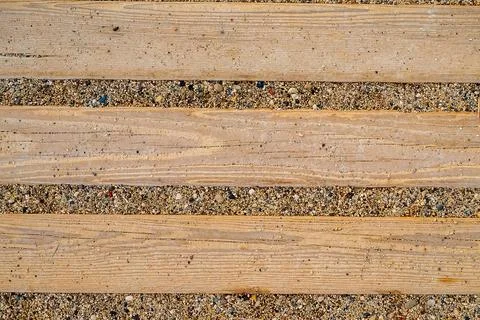 Wooden boards stretch across sandy ground in a public area. The sun shines do Stock Photos