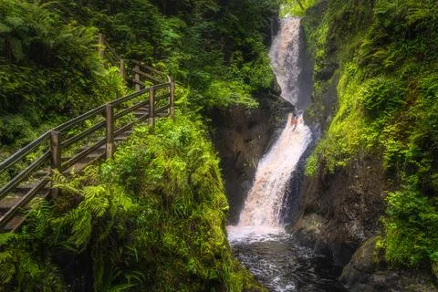 Wooden boardwalk on the hill with a view on tall waterfall and river in Stock Photos
