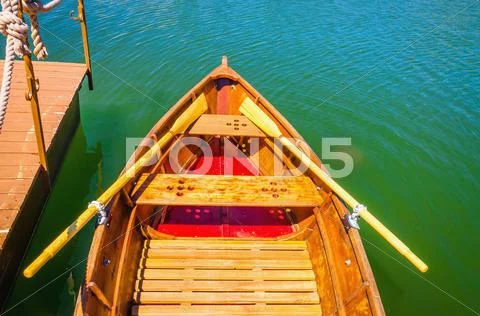 Wooden boat moored to a pier on the lake shore Stock Photos