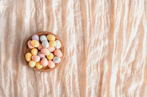 Wooden bowl filled with mini eggs on a beige background. Top view, copy space. Stock Photos