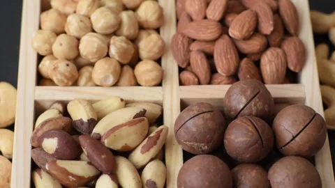 Wooden box with macadamia nuts, almonds, pistachios, and hazelnuts. Nuts as a fo Stock Footage 329622314