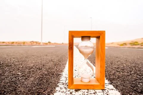 A wooden box with a sand timer inside is placed on a road 写真素材