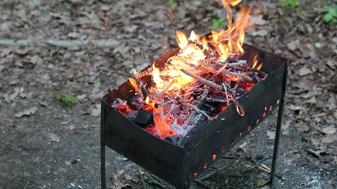 Wooden branches smoldering inside rustic metal brazier, producing glowing coals Stock Footage 297237114