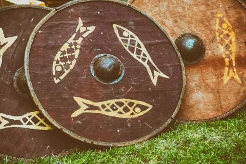 Wooden brown shield round with a pattern of fish stands on the ground rest on Stock Photos