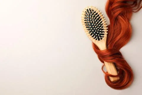 Wooden brush and red hair strand on light background, top view. Space for tex Stock Photos
