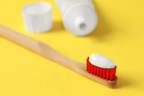 Wooden brush with toothpaste on yellow background, closeup 스톡 사진
