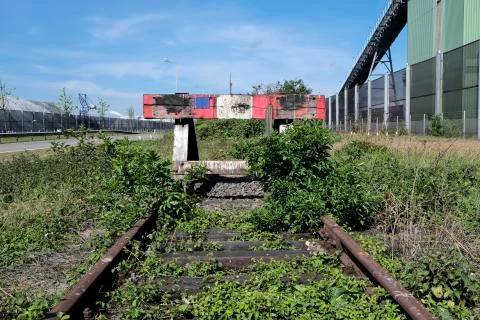 Wooden buffer stop with red stop sign ending rail tracks concept for limit Stock Photos
